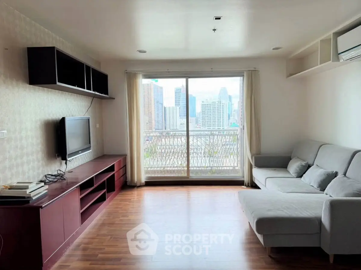 Spacious living room with city view, modern furniture, and large windows for natural light.