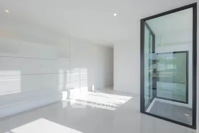 Modern minimalist interior with large glass window and sleek white walls, perfect for contemporary living.