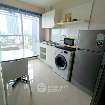 Modern kitchen with washing machine, fridge, and balcony view in high-rise apartment.