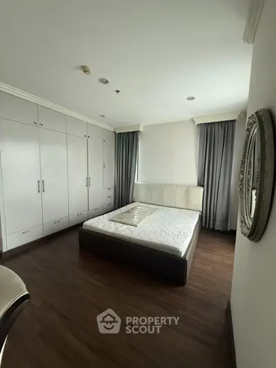 Spacious bedroom with elegant decor and ample closet space in modern apartment.
