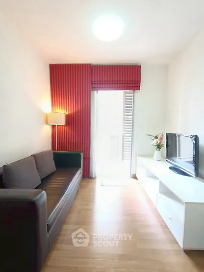 Cozy living room with modern sofa and TV unit, featuring bright red curtains and natural light.
