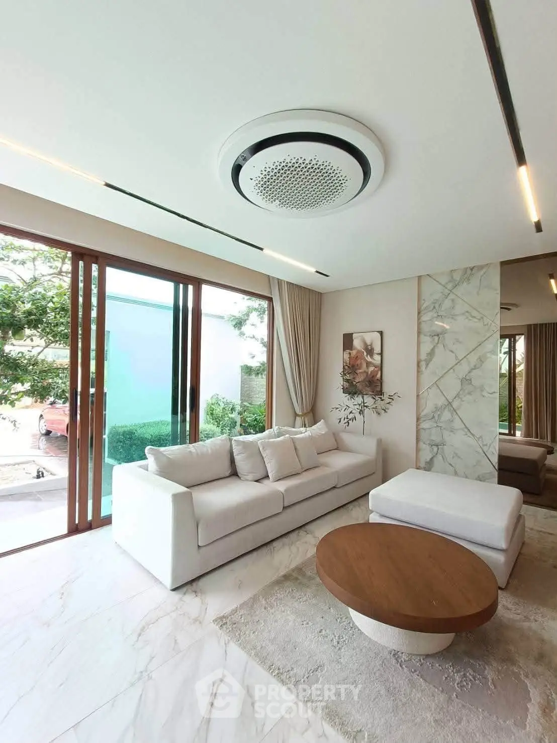Luxurious living room with modern decor, large windows, and elegant marble accents.
