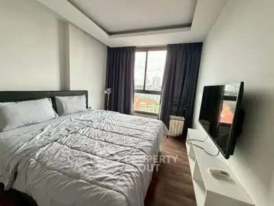 Modern bedroom with large window offering city view, featuring cozy bed and sleek TV setup.