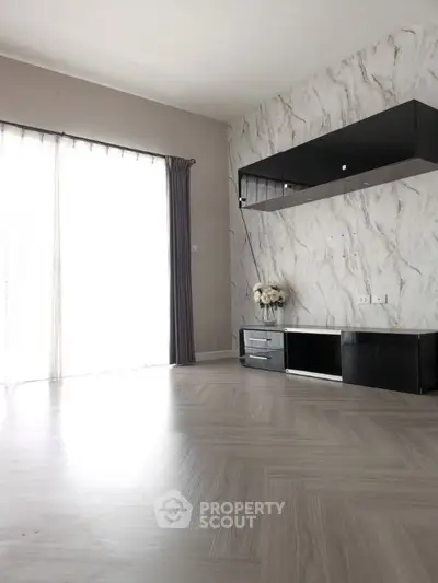 Modern living room with elegant marble accent wall and sleek black cabinetry.