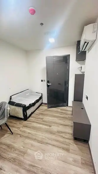 Modern minimalist bedroom with sleek flooring and compact furniture setup.