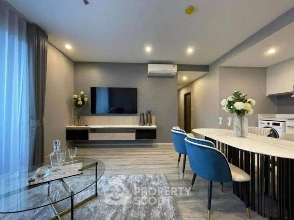Modern living room with elegant decor, featuring a sleek TV setup and stylish dining area.