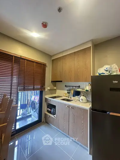 Modern kitchen with sleek cabinets and appliances, featuring a washing machine on the balcony.