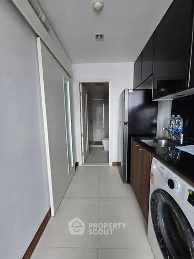 Modern kitchen with sleek appliances and washing machine in compact layout.