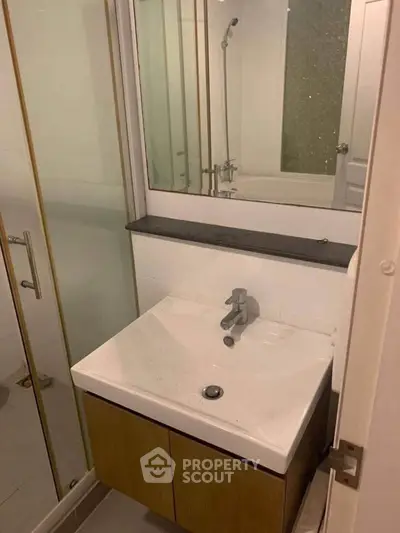Modern bathroom with sleek sink and glass shower enclosure in stylish apartment.