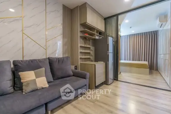 Modern living room with stylish decor and open view to bedroom, featuring sleek furniture and elegant design.