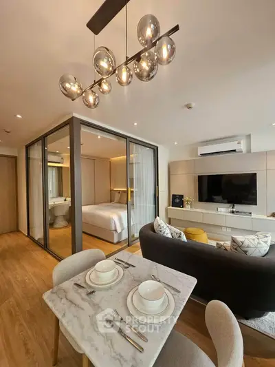 Modern open-plan living room with stylish lighting and cozy dining area in a contemporary apartment.