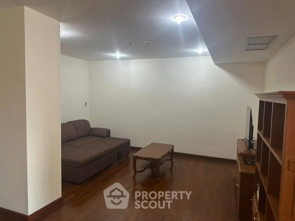 Spacious living room with wooden flooring and cozy furniture setup.
