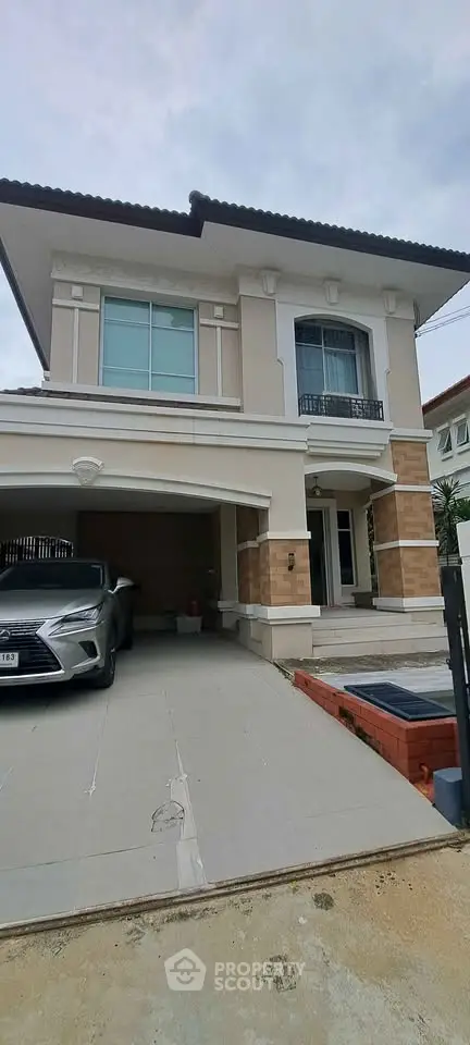 Elegant two-story house with modern facade and driveway featuring a luxury car parked in front.