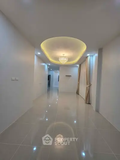 Spacious modern living room with elegant chandelier and glossy tiled flooring.