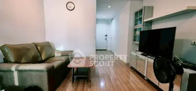 Modern living room with sleek wooden flooring, cozy sofa, and entertainment center, perfect for relaxation.