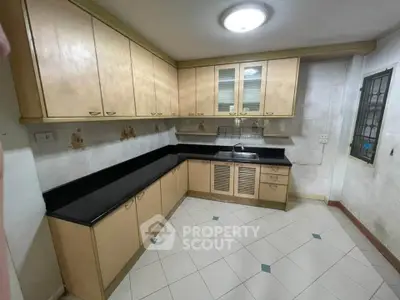 Spacious kitchen with ample cabinetry and sleek black countertops in a modern home.