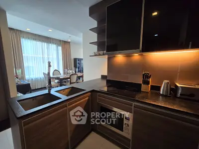 Modern kitchen with sleek design, featuring built-in appliances and open layout to dining area.