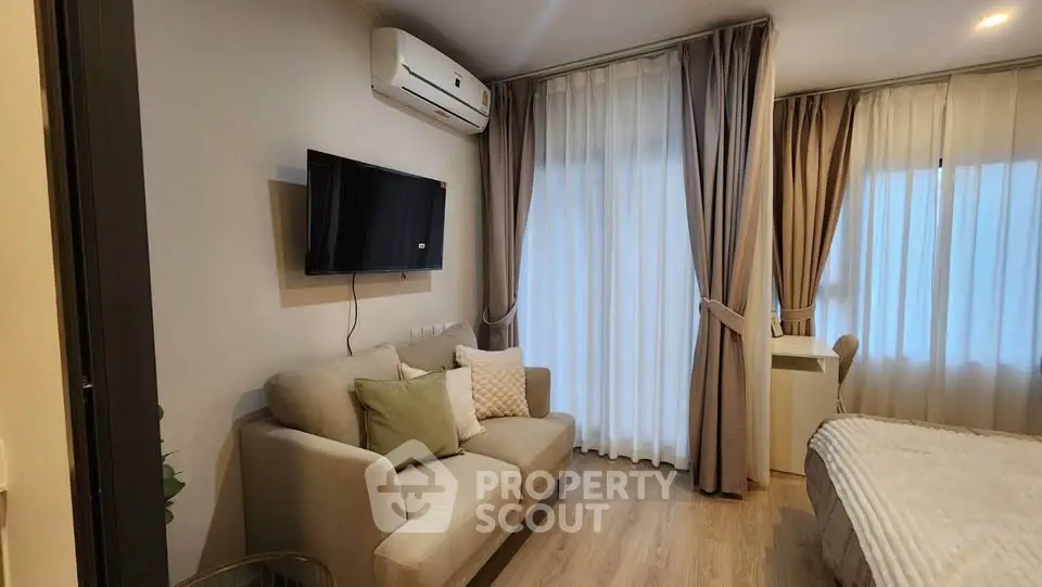 Cozy modern living room with sofa, wall-mounted TV, and elegant curtains in a stylish apartment.