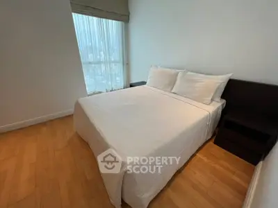 Cozy bedroom with large window and wooden flooring