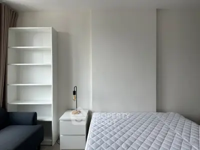 Modern bedroom with minimalist design featuring a cozy bed, sleek nightstand, and stylish shelving unit.