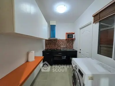 Modern kitchen with gas stove and washing machine, sleek cabinets and vibrant backsplash.