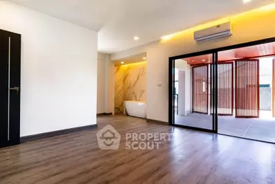 Spacious modern living room with wooden flooring and large sliding glass doors opening to a patio.