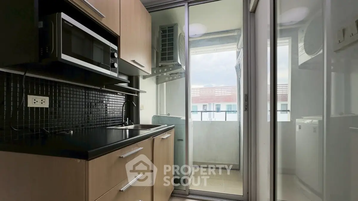 Modern kitchen with sleek cabinetry and balcony view