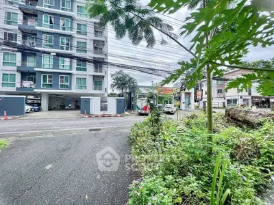 Modern apartment building exterior with lush greenery and parking area