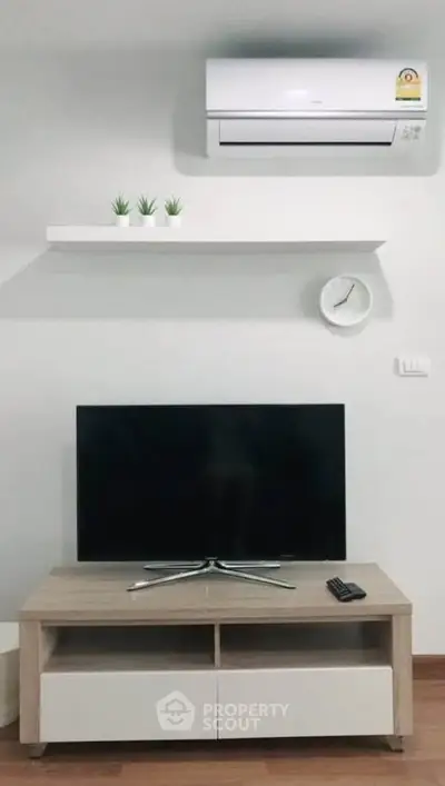 Modern living room with sleek TV setup and air conditioning, perfect for comfortable living.