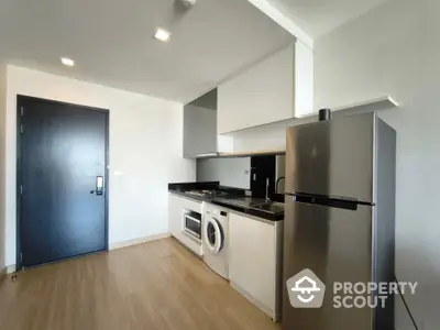 Modern kitchen with sleek appliances and wooden flooring in a stylish apartment.