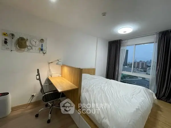 Modern bedroom with study area and city view, featuring sleek design and natural light.