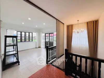 Spacious open-plan living area with elegant staircase and large windows for natural light.