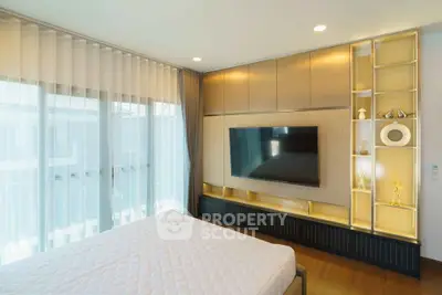 Modern bedroom with large TV and elegant shelving, featuring floor-to-ceiling windows and stylish decor.