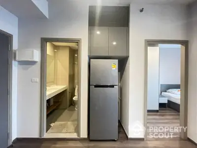 Modern apartment interior with fridge, bathroom, and bedroom access