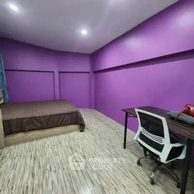 Spacious bedroom with vibrant purple walls and modern furnishings, ideal for a cozy living experience.