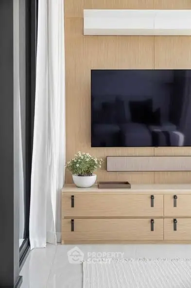 Modern living room with sleek TV setup and stylish wooden cabinetry.