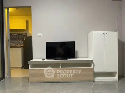 Modern living room with sleek TV stand and adjacent kitchen area in stylish apartment.