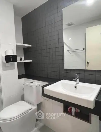 Modern bathroom with sleek black and white design, featuring a square sink and wall-mounted shelves.