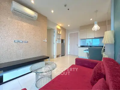 Modern living room with red sofa, glass table, and open kitchen layout