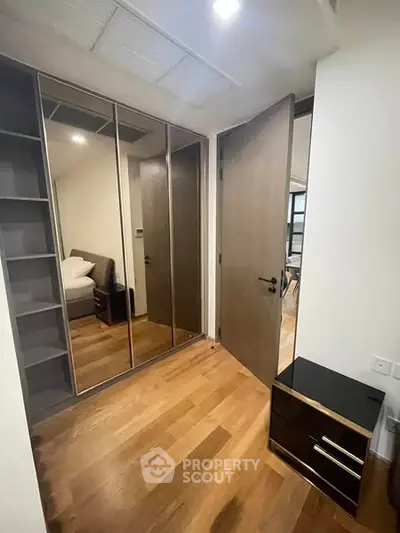 Modern bedroom with mirrored wardrobe and wooden flooring