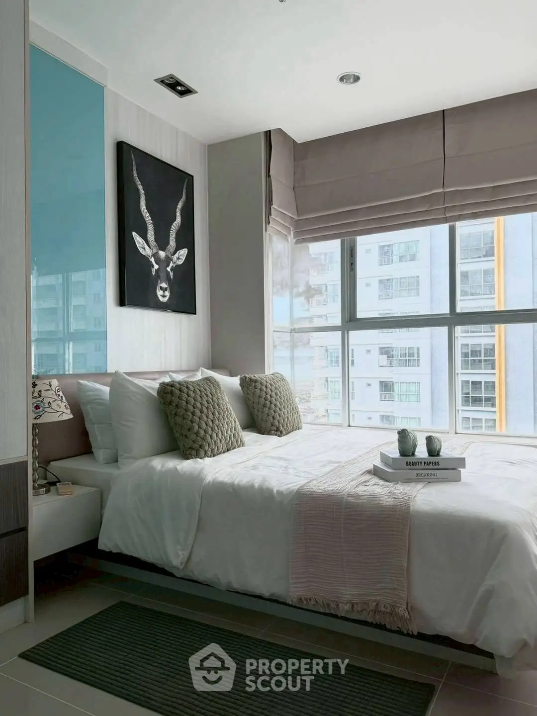 Modern bedroom with large windows and stylish decor in urban apartment.
