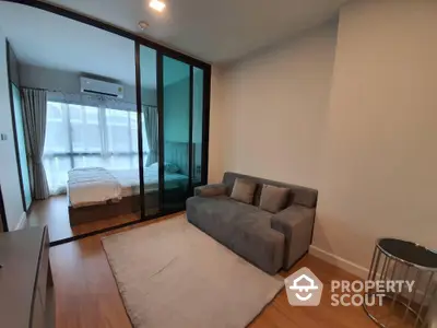 Modern studio apartment with cozy living area and bedroom separated by glass partition.