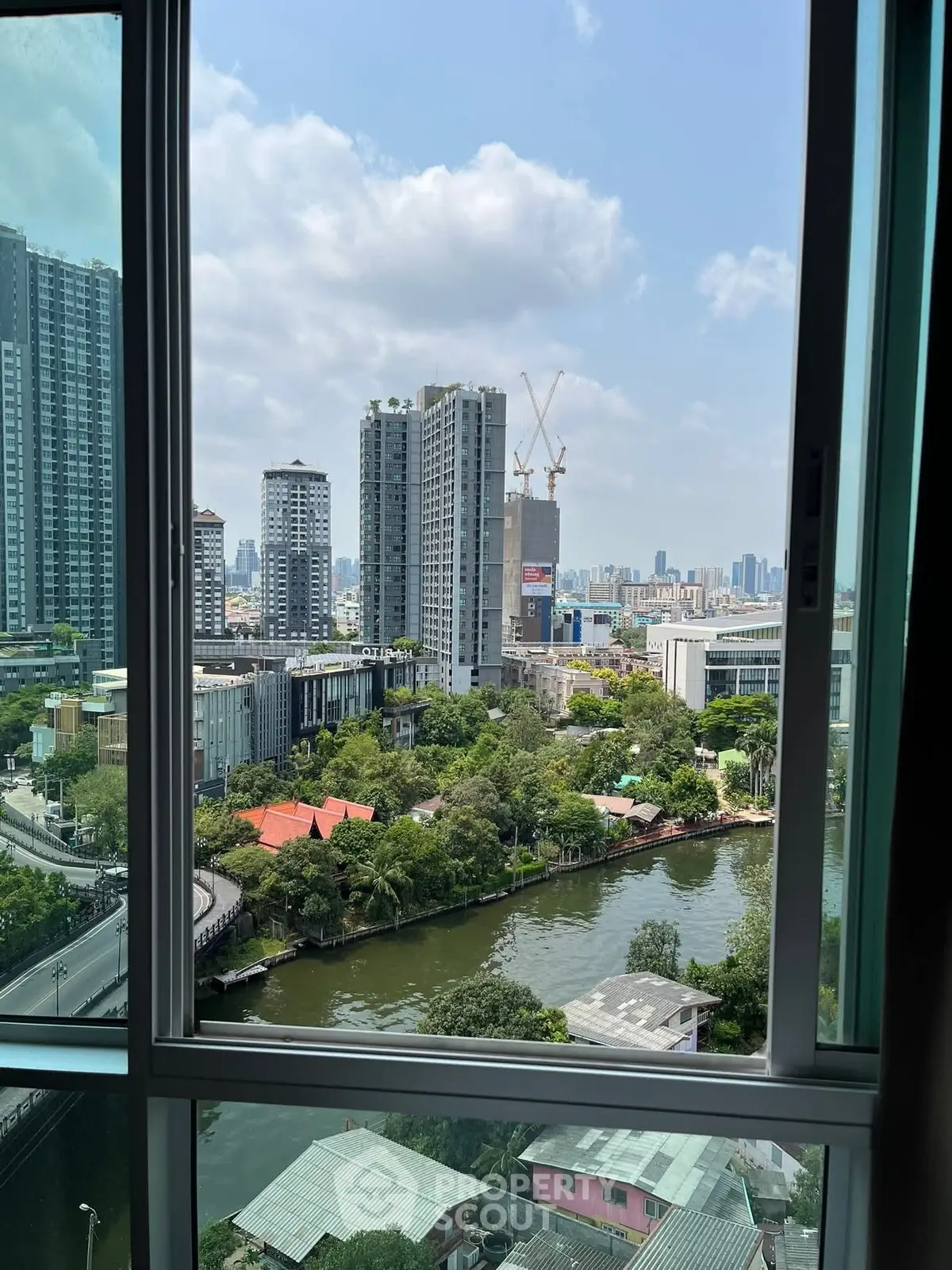 Stunning cityscape view from a high-rise window overlooking a river and modern buildings.