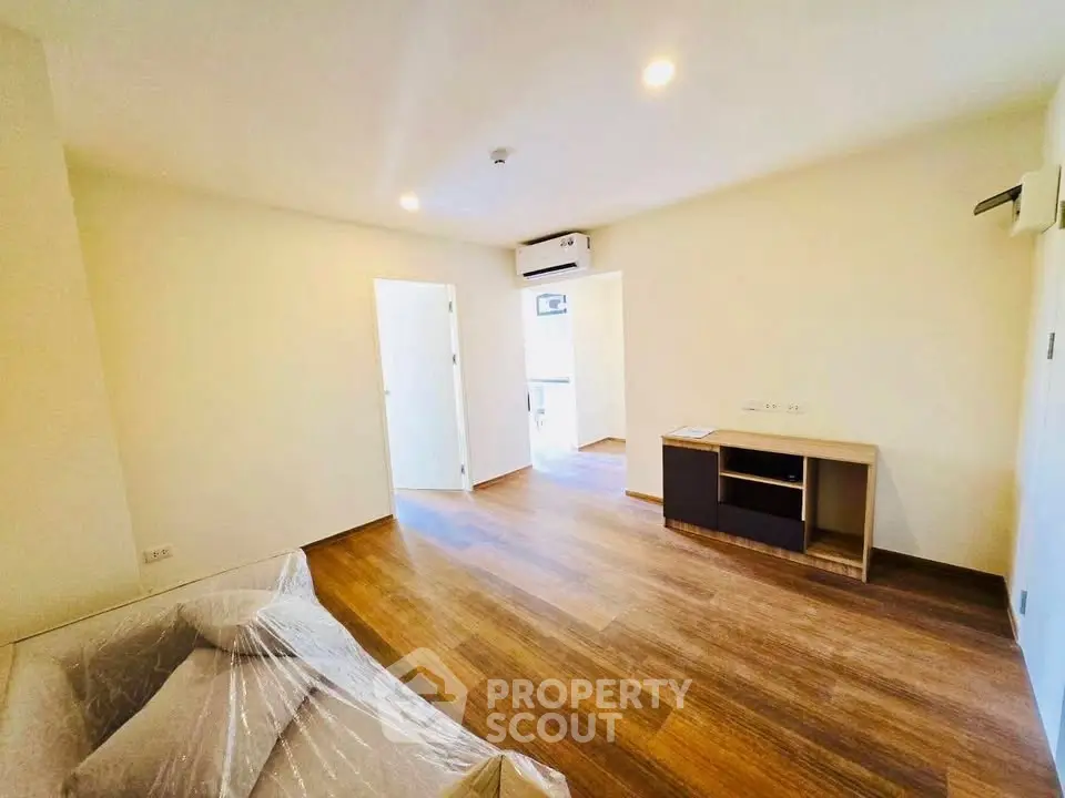 Spacious living room with wooden flooring and modern furniture in a bright apartment.