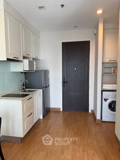Modern compact kitchen with washing machine and fridge in a cozy apartment.