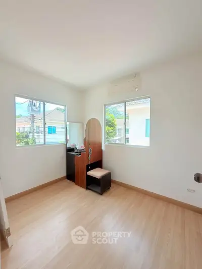 Bright bedroom with wooden flooring and large windows offering natural light and outdoor views.
