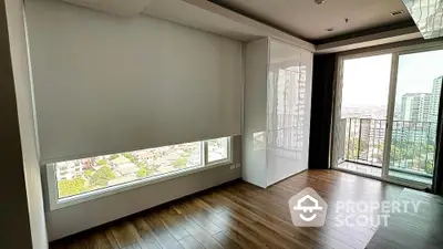 Modern apartment with large windows and city view, featuring sleek wooden flooring and balcony access.