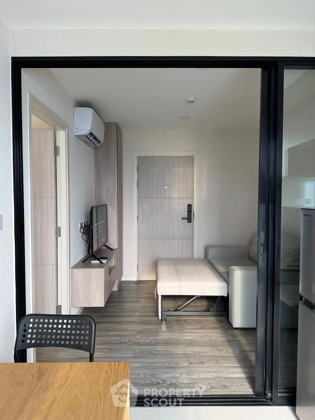 Modern living room with sleek furniture and air conditioning, featuring a cozy sofa and flat-screen TV.