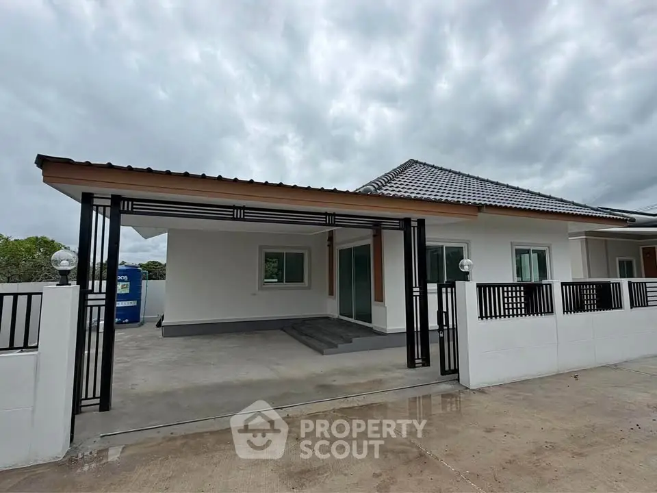 Modern single-story house with sleek design and spacious driveway under cloudy sky.