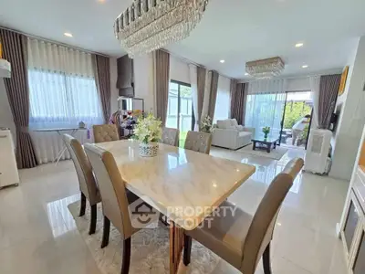 Luxurious open-plan living and dining area with elegant chandeliers and modern furnishings.